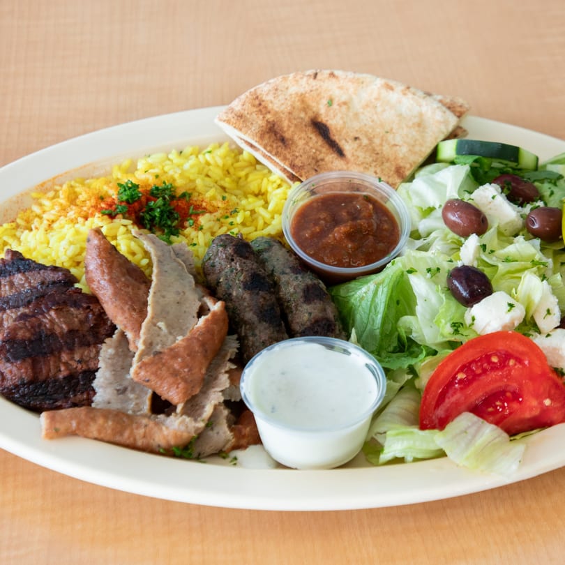 Safi Mediterranean Grill's mixed platter with grilled meats, yellow rice, pita, salad, and sauces.