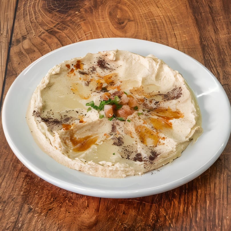 A plate of Safi Mediterranean Grill's hummus, drizzled with olive oil and spices on a wooden table.